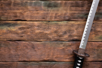 Katana sword on the brown wooden table background with copy space.