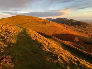 Panoramic landscape of Herefordshire and Worcestershire Beacon at sunrise with faint rainbow above...