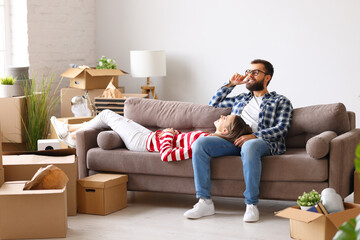 Couple resting on sofa after relocation in new apartment