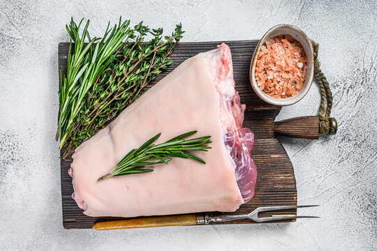 Raw Pork knuckle eisbein for cooking with herbs. White background. Top view