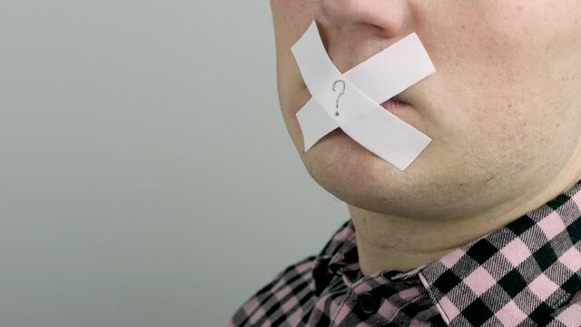 A man's mouth is closed, his lips are covered with sticky tape, a young man with a sticky plaster sealer over his mouth.