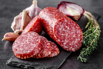 Traditional smoked salami sausage with spices.Salami sausage slices on a black chopping Board. Dark...