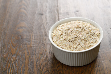 Ceramic bowl of rolled oats on dark stained hickory wood planks