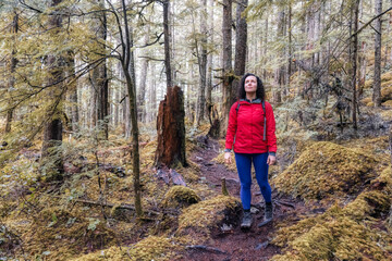 Fototapeta premium Girl Hiking on a Path in the Rain Forest during a rainy Winter Season. Squamish, North of Vancouver, British Columbia, Canada.