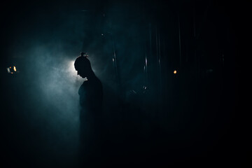 Silhouette of a young athlete in the gym, handsome torso of a man.