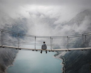 Mann sitzt auf einer Hängebrücke im Zillertal