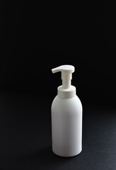 White bottle isolated on black background. Unbrending bottle for mockup. Dishwashing liquid is flowing from bottle.