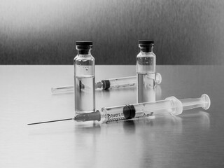 Syringes and ampoules on a polished metal background. Coronavirus vaccination and immunization...
