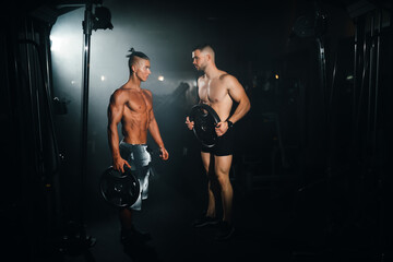Two young sports athletes show muscles in the gym, doing sports, healthy lifestyle.