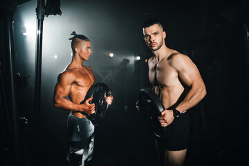 Two young sports athletes show muscles in the gym, doing sports, healthy lifestyle.