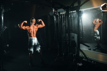 Fototapeta na wymiar Young sports athlete guy shows muscles in the gym, doing sports, healthy lifestyle.