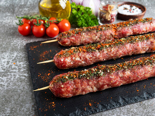lula kebab raw beef lamb on wooden skewer on a black stone surface, close up