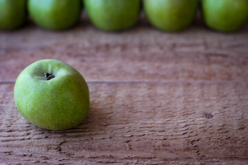 Green apples stand on a wooden surface