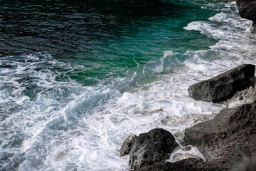 Dark stones, white ocean foam and waves. Bali island nature 