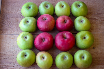 Green and red apples stand on a wooden surface