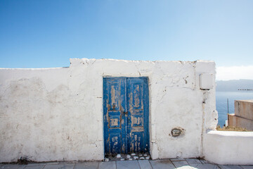 A white wall and a vintage blue door in the village of Oia - Santorini - Greece - Europe