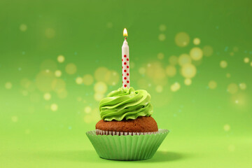 Cupcake with cream and a burning candle for a birthday or other holiday with a shopping plan on a colored background with bokeh lights 