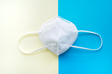white face mask isolated on a blue and yellow surface