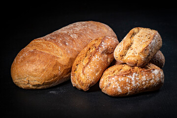 Fresh bread and rolls on a black kitchen table. Bread prepared for serving.