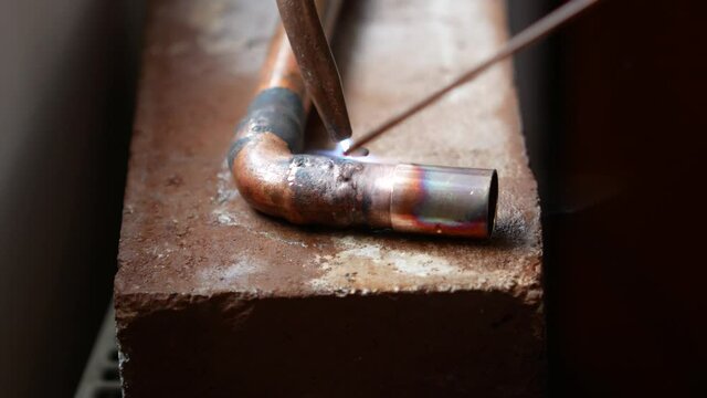 Close-up of autogenous welding of copper pipe, urgent repair welding of malfunctional home central heating system
