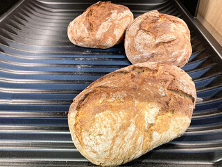 Three loaves of fresh bread on a supermarket shelf.