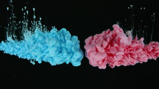 Underwater shot of colors that collide together and create abstract clouds. Red and blue ink on black background. Video in slow motion. 