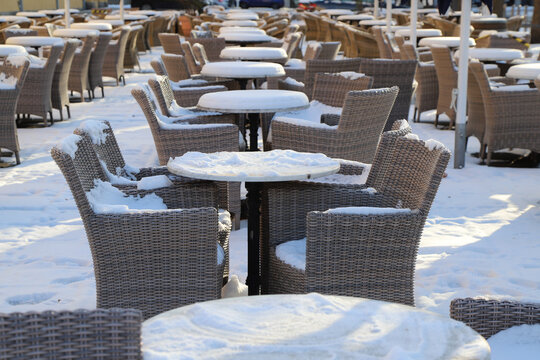 schneebedeckte outdoormöbel von einer außengastronomie im lockdown im winter in der stadt