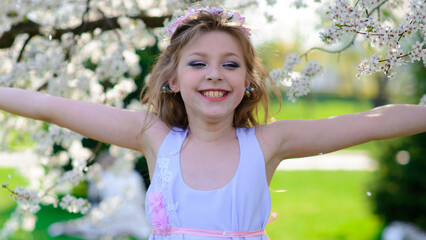 Pretty little girl in blooming apple tree garden on beautiful spring day