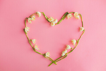 Happy Mothers day and love concept. Floral heart made of spring flowers on pink paper flat lay