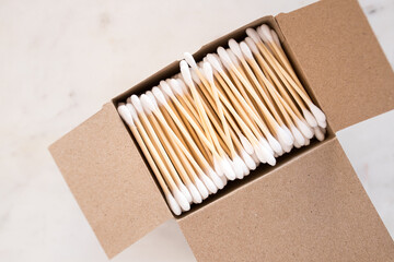 Opened cardboard box full of cotton swabs on a marble board.