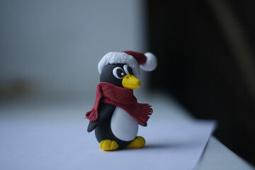 new year penguin in a santa claus  hat with pompon and red scarf sits on a white background and looks sideways