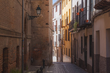 Narrow cobblestone backstreet in old town (Albaicin or Arab Quarter) in Granada, Andalusia, Spain.