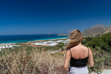 blond girl at turquoise beach Falasarna (Falassarna) in Crete, Greece. View of famous paradise sandy deep turquoise beach of Falasarna (Phalasarna) in North West, Crete island, Greece.