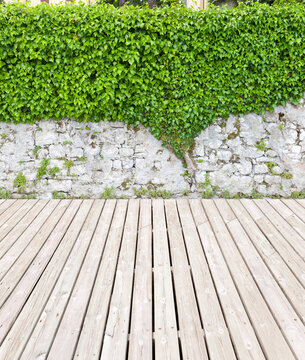 Nice garden terrace with overgrown wall and wooden floor. © Composer