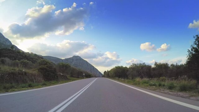 POV vehicle drive across mediterranean countryside, coastline rural scenery car travel, asphalt road point of view, olive trees orchards, clouds blue sky horizon