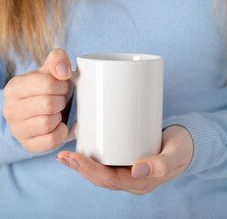 Female hands hold mock up white empty mug, cup for your design and logo closeup. Template blank for promotional text message or promotional content.