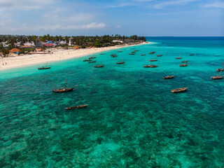 Traditional African Wooden Dhow Boats on Clean Turquoise Water near the Coast of Zanzibar at Nungwi Beach. Aerial Shot