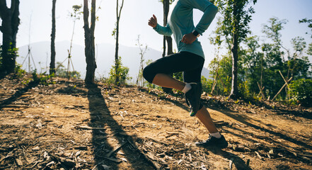 Young woman trail runner running in sunrise tropical forest mountain peak