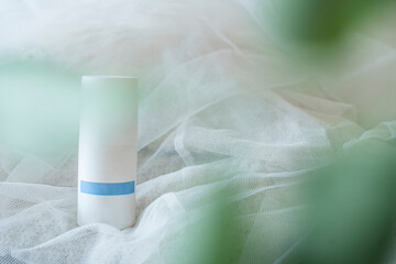 White deodorant with blurred green leaves on the foreground