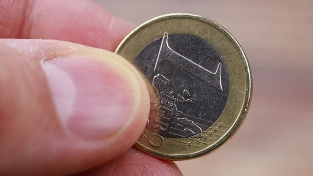 doigts tenant une pi&egrave;ve de 1 euro