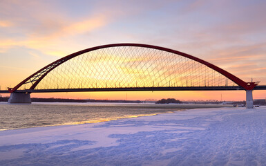 Winter sunrise on the Ob river. Bugrinsky automobile bridge on the frozen snow bank in Novosibirsk