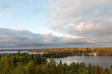 Panoramic view of peaceful lake scene with cabins surrounded by forrest.