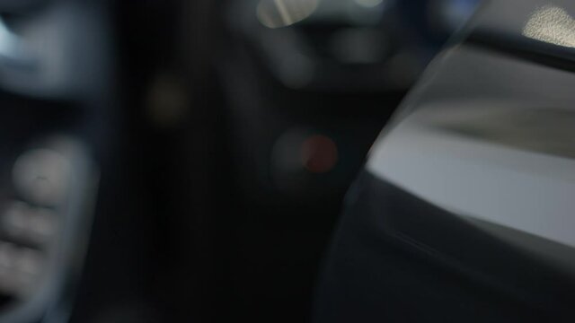 Close-up of unrecognizable girl opening luxurious black car door and sitting inside. Caucasian hand pulling door handle. Child in car dealership or garage. Slow motion.