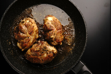 Large pieces of chicken fried in a frying pan. Top view.