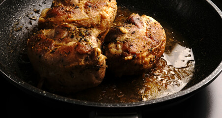 Large pieces of chicken fried in a frying pan.