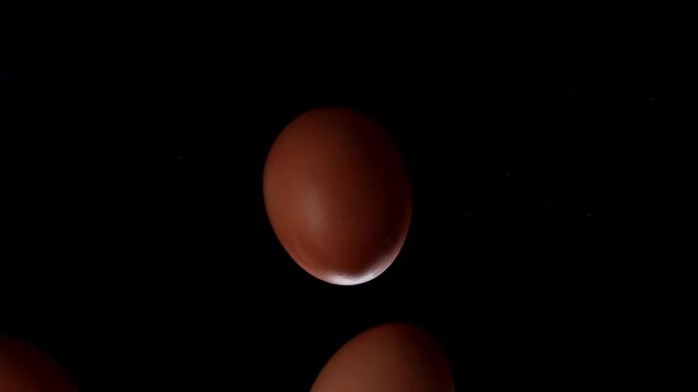 Egg is spinning on a black background. Slow motion of an egg in a shell spinning on glass. Close shot of a spinning egg.
