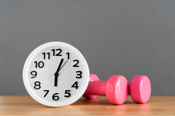 Time for exercising clock and dumbbell with gray color background