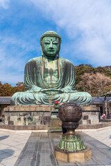 The Great Buddha, Daibutsu, with the incense burner in front, blue sky above in Kamakura, Japan