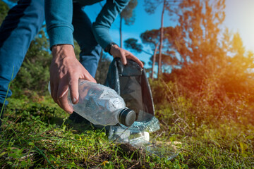 Man cleaning-up the forest of plastic garbage. Nature cleaning. Volunteer picking up a plastic...