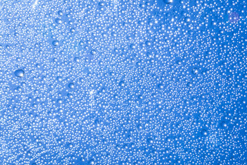 Rain drops on clear glass with sparkling sunlight On the blue sky background